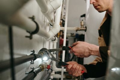 Technician inspecting commercial plumbing pipes in Laguna Beach