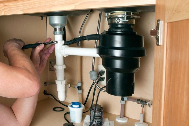 Plumber repairing a garbage disposal in Laguna Beach